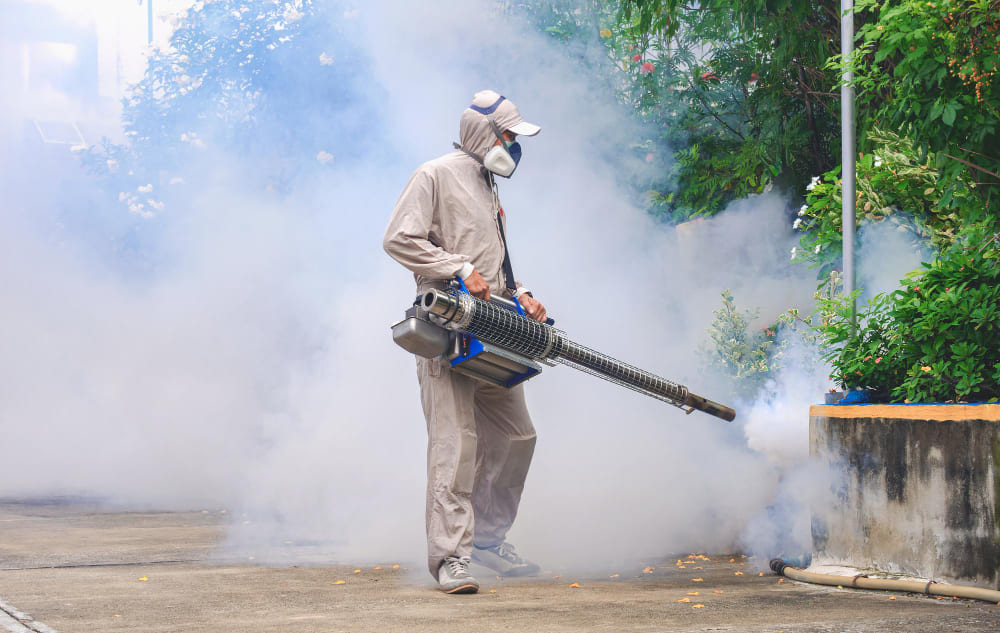 Pegawai pest control dengan hazmat sedang melakukan fogging untuk basmi nyamuk